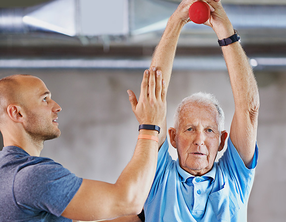 Man lifting weight getting assistance from trainer 